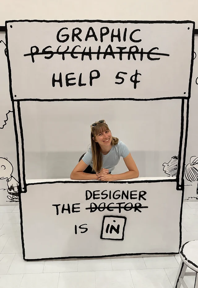 Abby smiling behind a playful, hand-drawn graphic design help booth